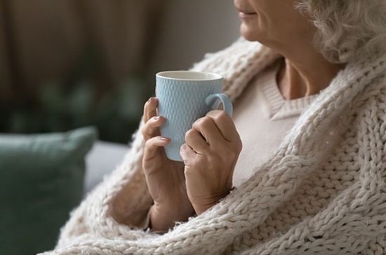 ältere Frau mit Tasse und Decke