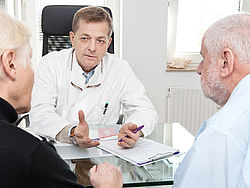 Arzt mit Patient und Angehöriger im Gespräch