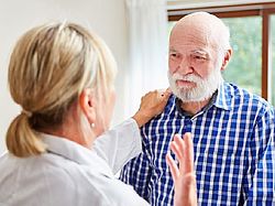 Ärztin spricht mit älterem Patient