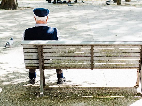 Alter Mann sitzt allein auf einer Bank