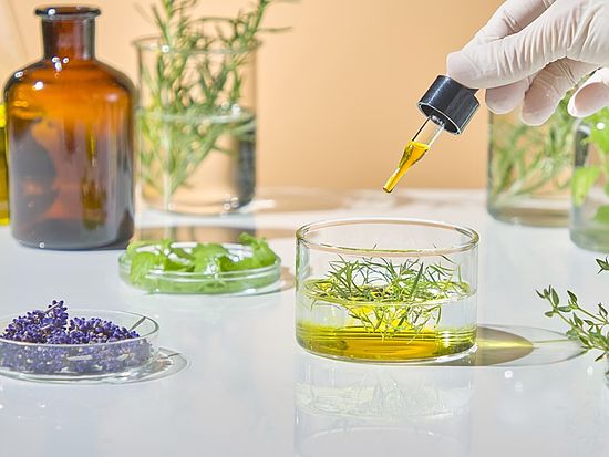 Hand eines Labormitarbeiters mischt ätherische Öle und Kräuterextrakte.