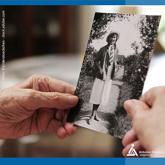 Seniorin hält ein altes Foto in den Händen