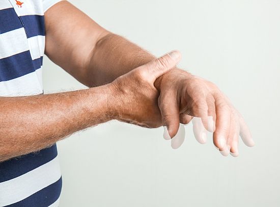Mann hält seine Hand fest, Symbolbild für Parkinson-Krankheit