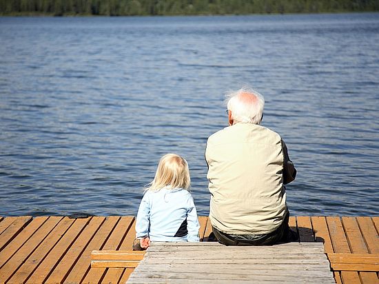 Opa sitzt mit Enkel auf einem Steg