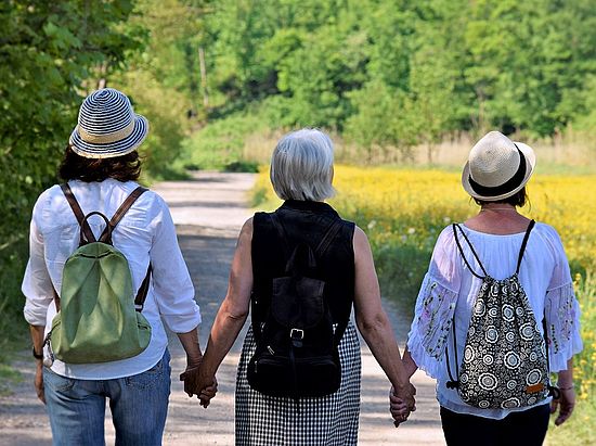 Drei Frauen gehen Hand in Hand spazieren