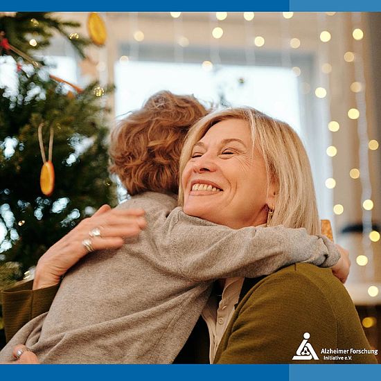 Kind und Seniorin umarmen sich vor einem Weihnachtsbaum