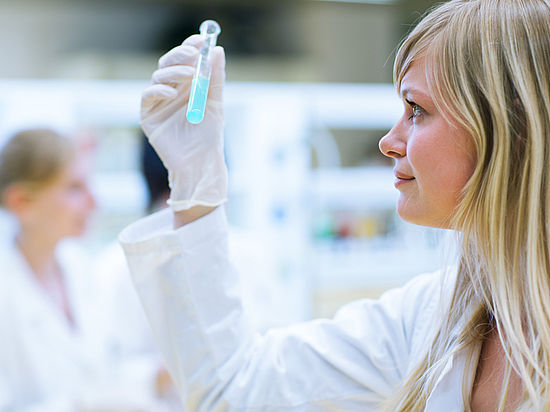 Wissenschaftlerin im Labor mit Reagenzglas in der Hand
