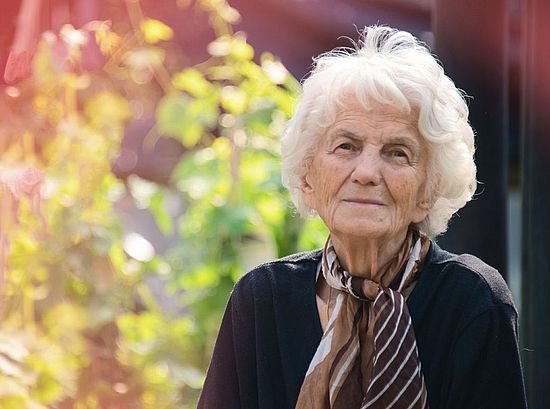 ältere Frau mit Pflanzen im Hintergrund