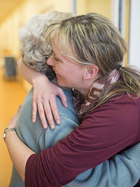 Pflegerin umarmt eine Seniorin