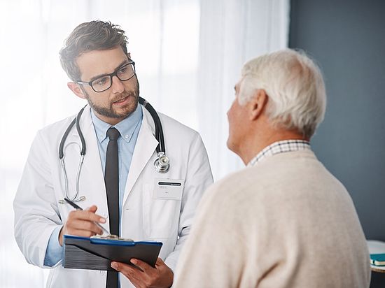Arzt spricht mit älterem Patienten in einer Praxis.