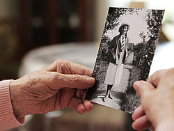 Hände einer älteren Person halten das Schwarz-Weiß-Foto einer jungen Frau
