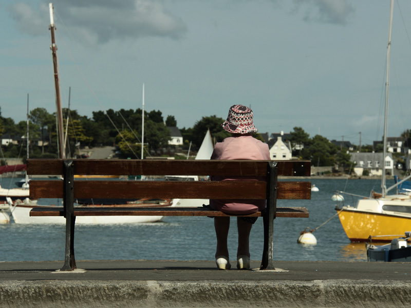 Eine Frau sitzt auf einer Bank am Hafen